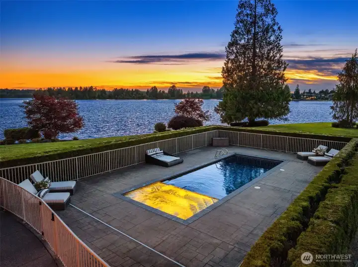 Heated in-ground pool & hot tub surrounded by privacy hedge.