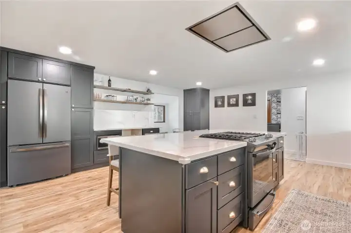 A large modern chef’s kitchen features an open layout with sleek cabinetry, a spacious island with bar seating, stainless steel appliances, and quartz countertops. Ample storage, and built-in refrigeration make it functional, while minimalist design, clean lines, and statement lighting add a sophisticated, contemporary look.