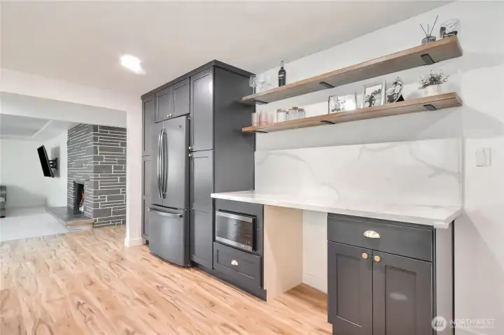 Modern trendy kitchen with stainless steel appliances and desk or wine frig area.