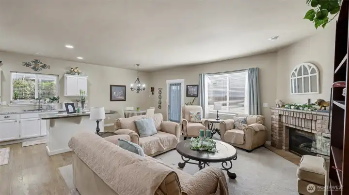 The living room is anchored by a stunning brick fireplace that creates a warm, welcoming focal point, while refinished hardwoods and newer carpet add a fresh, updated feel throughout.