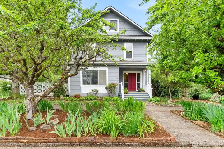Beautiful curb appeal with established greenery and inviting front porch entry.