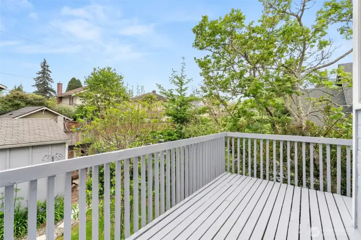 Second-story deck surrounded by mature greenery, offering a peaceful outdoor retreat