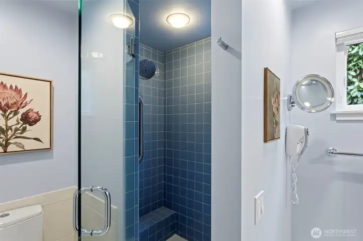 The bathroom features heated floors, a walk-in shower with shampoo niche, beautiful tile work and another wall mounted vanity faucet