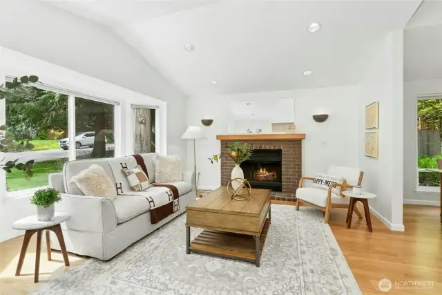 Formal living room with a cozy fireplace and a wall of windows allowing for lots of natural light.