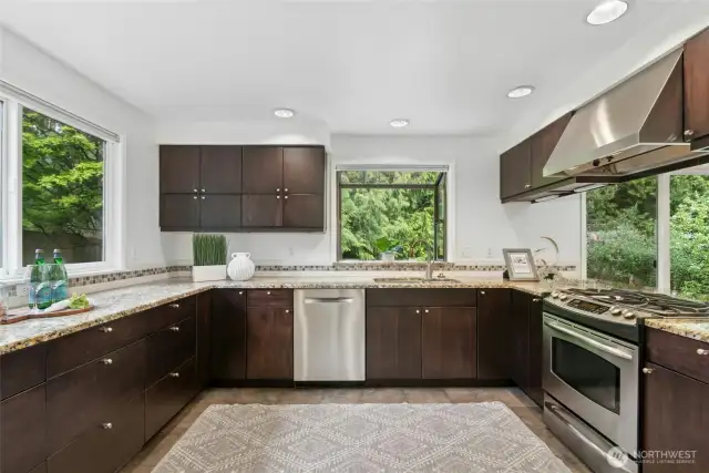 A delightfully updated kitchen, boasting abundant cabinetry, sleek stainless steel appliances and heated tile flooring.