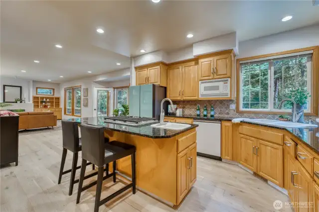 Another view of the kitchen showing off the eating bar with gas cooktop and prep sink.