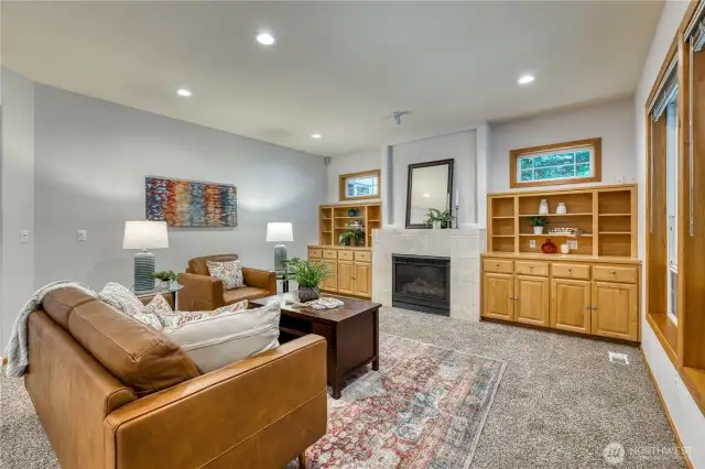 View of the cozy family room with gas fireplace and beautiful built-ins. Views to the right of backyard and patio area.