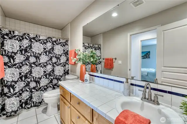 Guest bath with long tile topped vanity, tiled shower and floor.