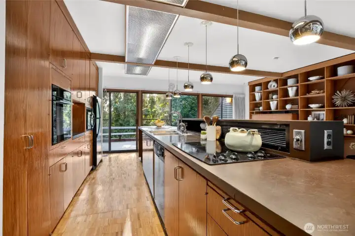 Open concept kitchen with restored hardwood floors and cabinetry, original mid-century modern light fixtures