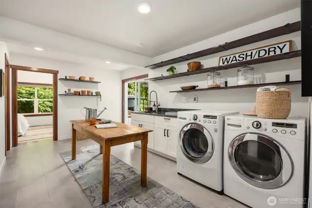 The laundry room is also a mudroom with a sink, built-in storage, shelving and plenty of room for an office space or crafts room.