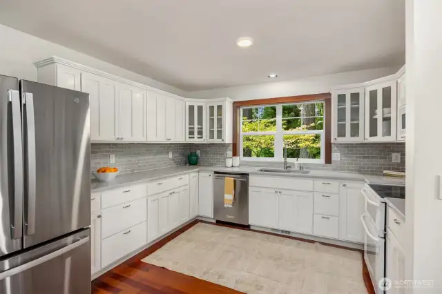 The kitchen has quartz counters, tile surround backsplash, farm sink and wood cabinets.