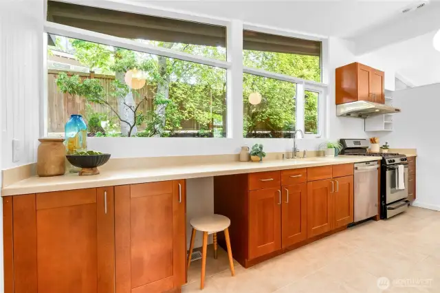 Kitchen glass windows overlook the backyard and natural surroundings.
