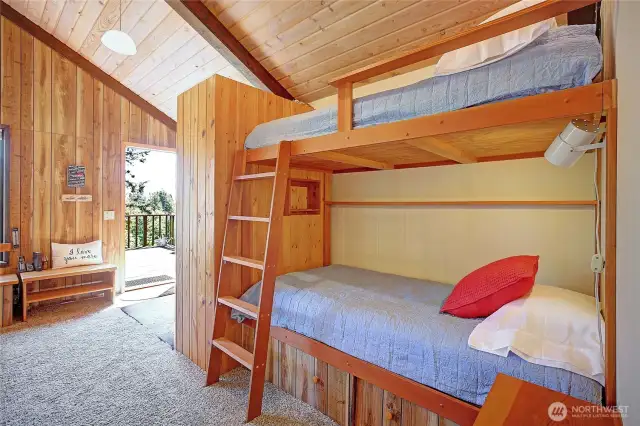 Adorable bunk beds with reading lights, book shelf and cubbies adorn this space.