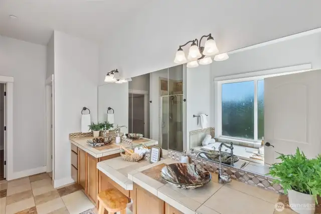 This stunning 5-piece bath features stunning dual vanities with amazing storage.  Notice the floor to ceiling tile shower in the mirror's refection. A large walk-in closet completes the en-suite.