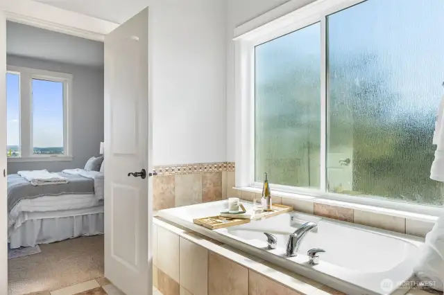 Soak your cares away in this stunning soaking tub with tile surround and large rain shower privacy windows.