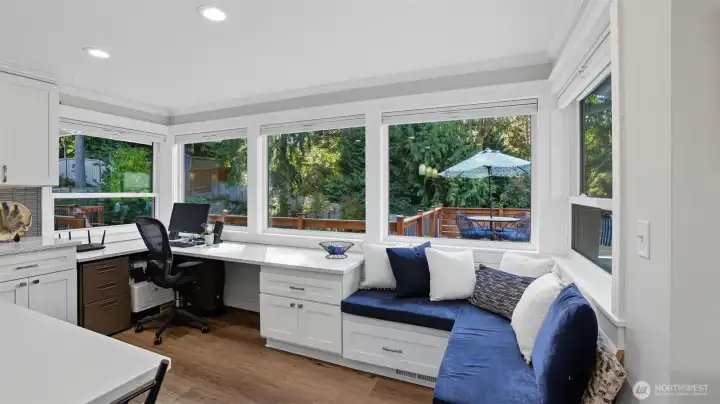 Bench seating and a desk planning station are surrounded by large windows with views of the expansive deck and yard.