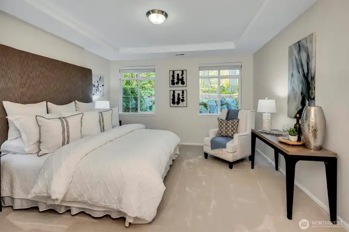 Spacious primary suite with coved ceiling, easily accepts a large king size bed with headboard and two full-size nightstands, and a dresser.