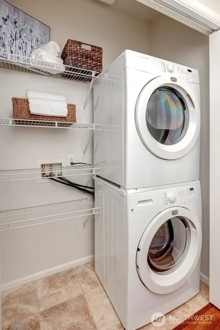 Hallway laundry closet with stacked unit that stays with the home. Storage shelves for pantry or costco storage, and clothes detergents. Could modify this space with a side-by-side placement with a built-in folding counter over the top and cabinets overhead.