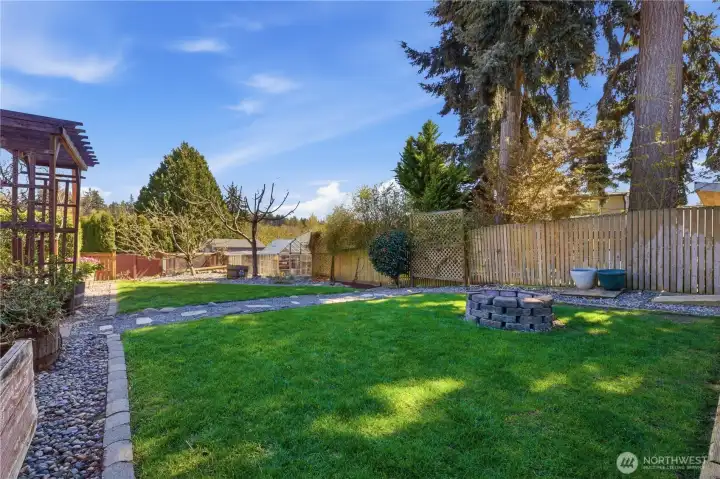 Park-like, fully fenced yard with chicken coup, greenhouse and RV parking with hook-up