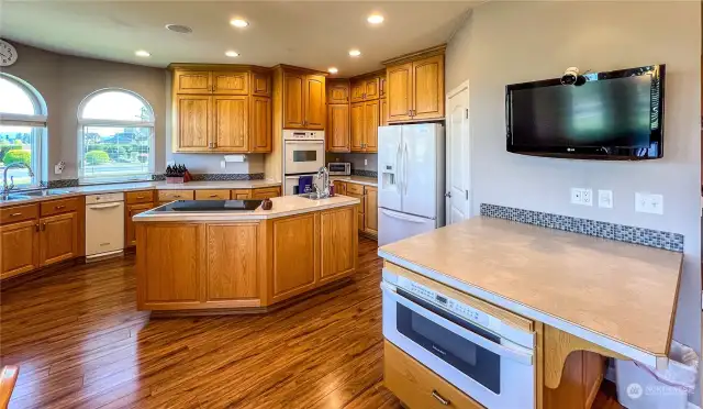 Another view of the spacious kitchen with ample cabinets and counter space. There is also bar seating, walk in pantry, trash compactor, double ovens, induction cook top, refrigerator and micorwave.
