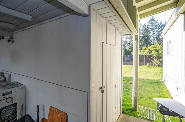 A convenient storage shed is situated at the end of the covered carport, with the backyard extending just beyond.