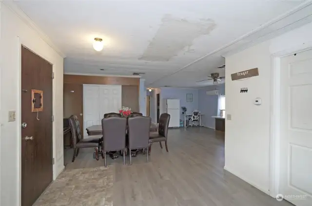 View from the front entry showcasing the dining area and kitchen. The ceiling mark is not a stain—it’s where the front coat closet was removed.