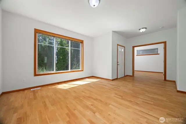 The front entry opens into the living room with white oak floors on the main level. To the right of the entry is a bedroom or office space with French doors.