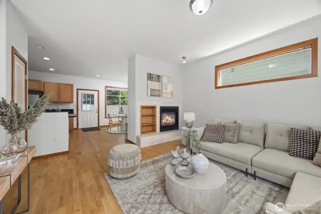 Looking across the living room with the entry and bedroom to the left and the double-sided fireplace to the right and the kitchen and coat closet in the middle.
