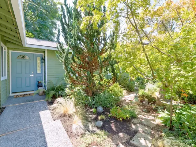 Mature garden plants and trees welcome you to front door