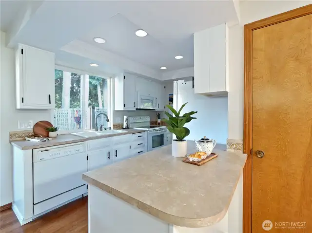 Efficient kitchen with can- lit tray ceilings; one of two pantries shown