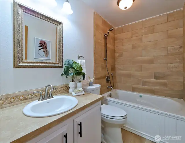 Master bath has jacuzzi tub, tile enclosure, backsplash and floor, porcelain sink