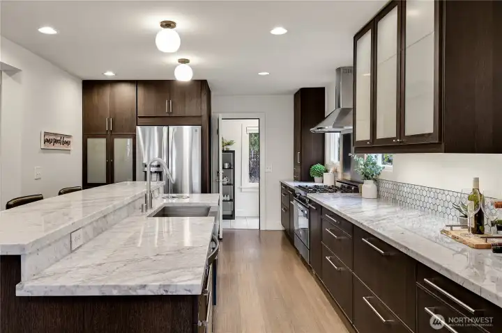 The heart of the home is its open-concept kitchen, a chef’s dream with marble countertops, stainless steel appliances, and custom cabinetry. French doors from the dining area lead to a spacious deck, perfect for entertaining or enjoying serene views of the surrounding landscape. Whether hosting a dinner party or savoring a quiet morning coffee, this space is designed for both elegance and ease.