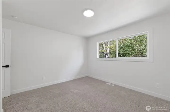 The bedroom looks out onto the backyard, bringing in natural light and a sense of privacy.
