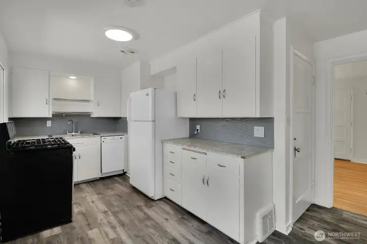 Sunny kitchen with a gas range. The door on the right opens to the lower level stairwell. Sunny kitchen with a gas range. The door on the right opens to the lower level stairwell.