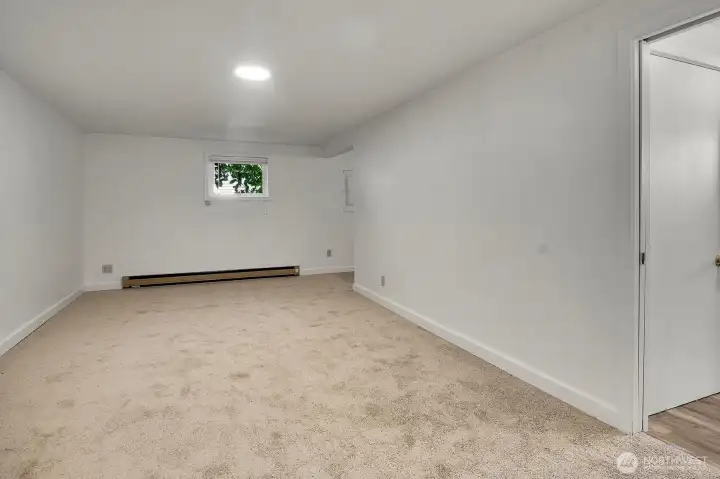 Lower level rec room. The door to the right opens into the kitchen area, and the opening at the back of the room leads to the bathroom. Lower level rec room. The door to the right opens into the kitchen area, and the opening at the back of the room leads to the bathroom.
