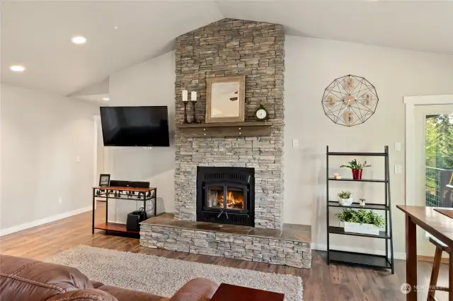 Stacked ledgestone fireplace with hearth & mantle. This woodstove will be replaced with the original propane insert for the new buyers! Attached TVs stay! & home is wired inside & out for speakers.