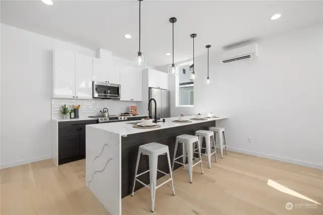 Sleek, modern kitchen featuring an oversized waterfall island with seating, perfect for casual dining and entertaining.