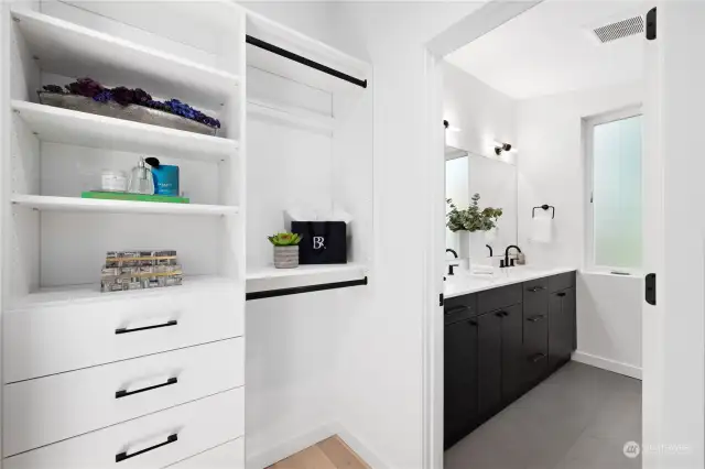 Custom walk-in closet leading to a modern bathroom with dual sinks and elegant fixtures.