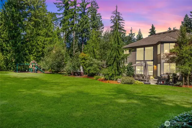 Expansive lawn framed by mature trees and manicured gardens.