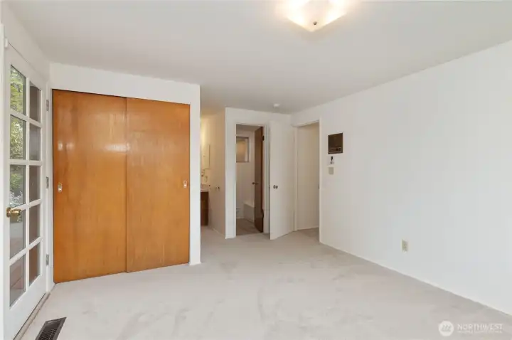 primary bedroom showing primary bath, door to hall, french door, one of two closets