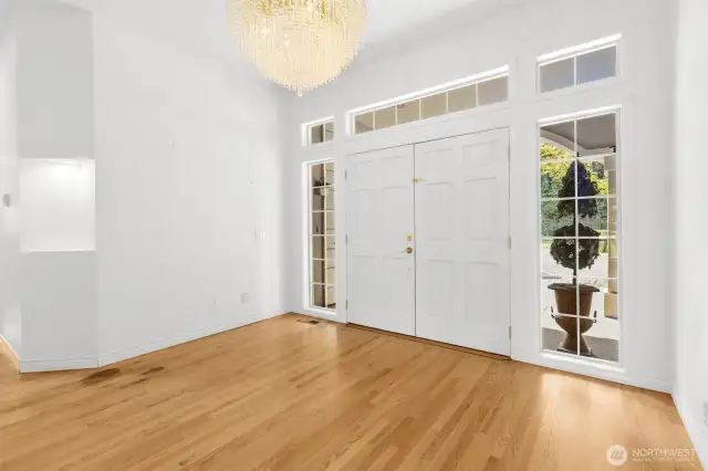 Double door entry with elegant chandelier, hardwood floors and decorative niches.