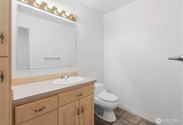 Guest half bathroom with tile flooring and large vanity with additional storage.