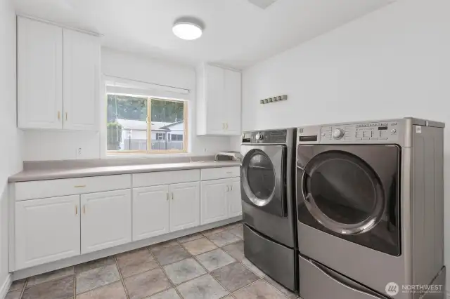 Spacious utility room with tile floors, ample storage and counter space. Conveniently located off oversized 3-car garage too!