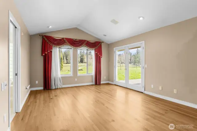 Primary bedroom with hardwood floors, vaulted ceilings and French door access to backyard and patio.