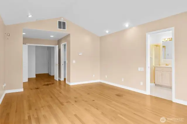 Spacious primary bedroom with double door entry, hardwood floors and custom walk-in closet.