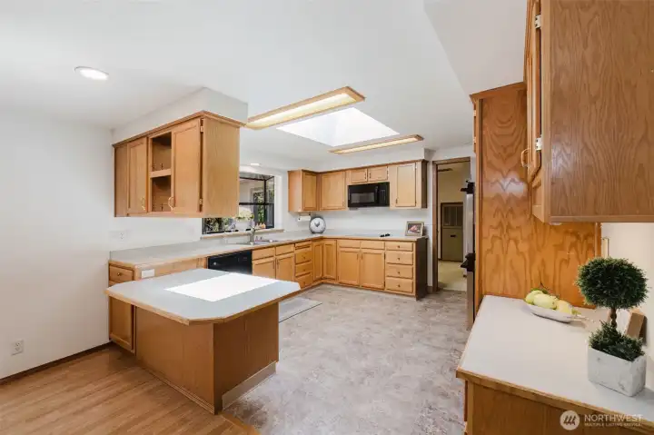 The spacious kitchen is both functional and charming, featuring generous counter space, abundant cabinets and drawers, and a built-in desk for added convenience. A garden window adds natural light, while an open, see-through cabinet connects to the dining area—perfect for displaying favorite dishes or keeping conversation flowing. The kitchen is well-equipped with a flat-top stove, brand new microwave, and double ovens, making it ideal for everyday cooking or entertaining.
