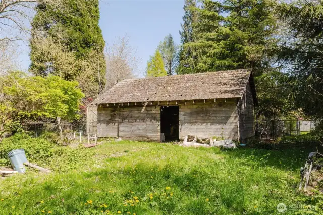 At the back of the property, you'll find a rustic barn that adds picturesque character to the landscape. While it shows its age—with some sunlight peeking through the roof and siding boards—it's still standing strong and has potential for restoration. A small deck sits nearby, offering a perfect spot to sit and take a break while enjoying the peaceful surroundings. With a little attention, this barn could be brought back to life and become a charming feature of the property once again.
