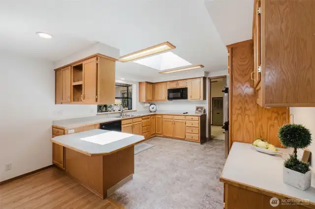 The spacious kitchen is both functional and charming, featuring generous counter space, abundant cabinets and drawers, and a built-in desk for added convenience. A garden window adds natural light, while an open, see-through cabinet connects to the dining area—perfect for displaying favorite dishes or keeping conversation flowing. The kitchen is well-equipped with a flat-top stove, brand new microwave, and double ovens, making it ideal for everyday cooking or entertaining.