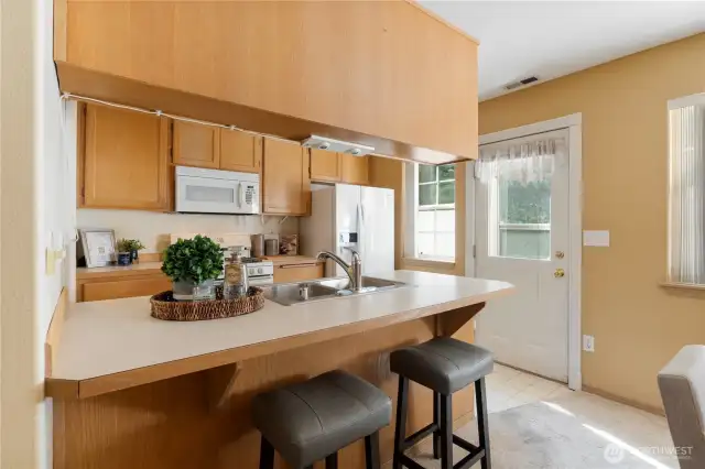 The kitchen has bar seating and an open flow to the dining room. Note the door to the private outside deck.