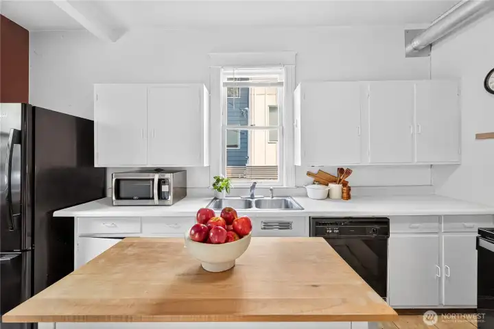 Functional kitchen with movable island, full appliance package, and window above the sink for natural light.